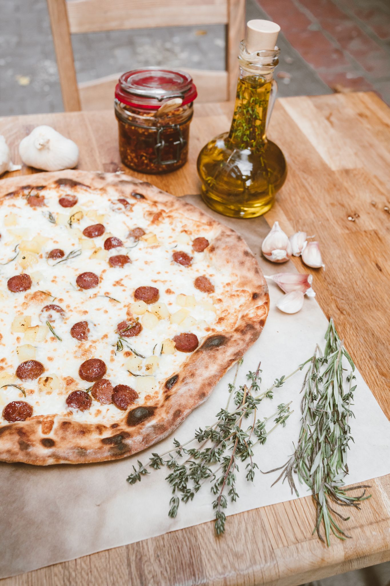 Mouth-watering pepperoni pizza with herbs, garlic, and olive oil on a rustic table.